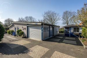 a house with a garage and a building at Summer house on quiet park close to beach in Ouddorp