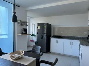 コベニャスにあるApartamento Caribe Coveñasのキッチン(黒い冷蔵庫、白いキャビネット付)