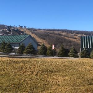 a building on the side of a road next to a field at Beechview Condo in Beech Mountain