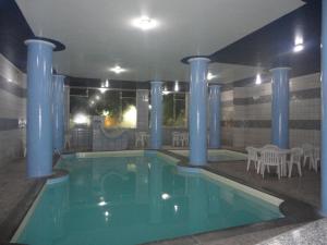 a swimming pool with blue columns and a table and chairs at Jóia Hotel in Poços de Caldas