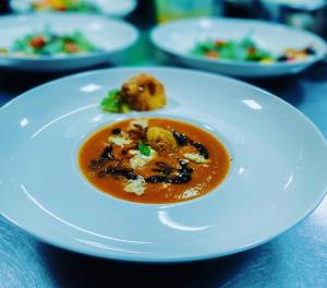 un piatto bianco con una ciotola di zuppa su un tavolo di Gasthaus Tschiffra a Blitzingen
