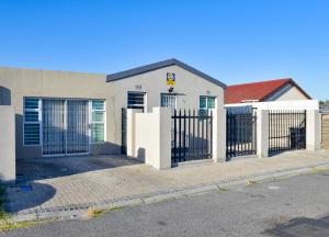 a white house with a gate and a fence at Blade Flatlet in Silver Sands