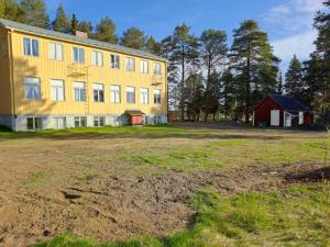 un grande edificio giallo con un fienile rosso e un campo di Skolan a Gargnäs