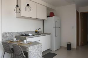 a kitchen with a refrigerator and a table with chairs at Resort beira-mar Porto Galinhas in Porto De Galinhas