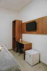 a room with a desk and a television on a wall at Hotel Villa Garden Janaúba-MG in Janaúba