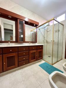 een badkamer met douche, wastafel en spiegel bij Descomplica Hostel in Assis