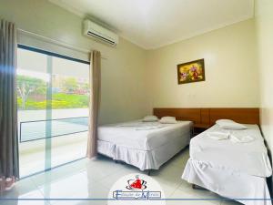 two beds in a room with a large window at Hotel Estação de Minas in Aparecida +29 photos