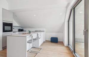 eine Küche mit weißen Schränken und einer Theke mit Stühlen in der Unterkunft 2 Bedroom Gorgeous Apartment In Tossens in Stick