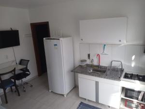 a small kitchen with a white refrigerator and a table at Studio em São José SC in São José