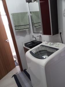 a bathroom with a toilet with a sink and a mirror at Studio em São José SC in São José