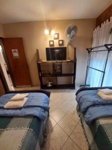 a room with two beds and a flat screen tv at Departamento interno con dos camas individuales in Córdoba