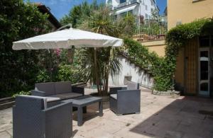 斯培西亚Small Luxury Bed & Breakfast的庭院配有桌子、遮阳伞和椅子