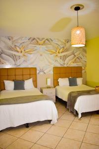 a bedroom with two beds with a mural on the wall at Hotel Boutique Valverde Santa Elena in San Salvador
