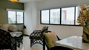 a living room with a table and chairs and windows at Park View Hostel & Suites in Manta