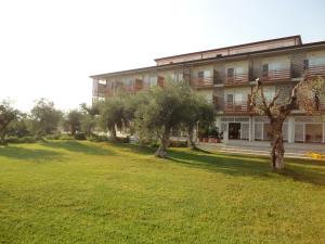 a building with trees in front of a green field at Elaia Garden Hotel in Sperlonga