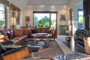 a living room with a leather couch and a table at Sunrise Serenity with Hot Tub in Christchurch