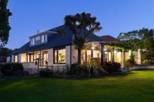 a house with a palm tree in front of a yard at Sunrise Serenity with Hot Tub in Christchurch