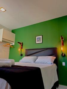 Un dormitorio con una pared verde con una cama. en Loft Biliu, en Campina Grande