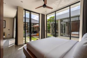 a bedroom with a large bed and large windows at Solencia Villa by Betterplace in Jimbaran +37 photos