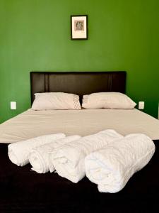 Un dormitorio verde con una cama grande con sábanas blancas. en Loft Vava, en Campina Grande