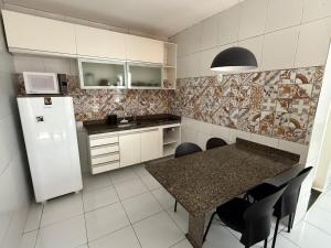 a kitchen with a table with chairs and a refrigerator at Loft Vava in Campina Grande