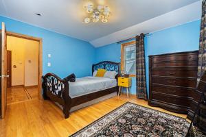 a bedroom with a bed and a dresser and blue walls at Extremely Spacious Home 10 Mins to The Encore in Medford