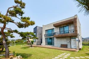a house with a balcony and a tree at Daebudo Grace Ocean View Private House in Ansan