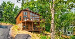 Stunning Cabin for 6 with Hot Tub & Pool Table في سيفيرفيل: منزل خشبي كبير على تلة في الغابة