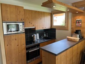 a kitchen with wooden cabinets and a microwave at Appartement confortable au Grand-Bornand pour 5 personnes - FR-1-467-146 in Le Grand-Bornand +3 photos