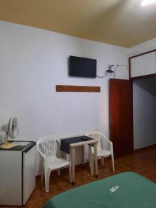 a room with a table and chairs and a tv on the wall at Pousada Silva Guedes in São Thomé das Letras +52 photos