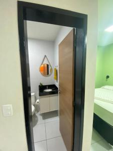 una habitación con un baño con una cama y un espejo en Loft Dominguinhos, en Campina Grande