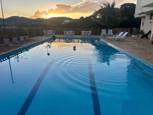 una grande piscina blu con un tramonto sullo sfondo di Recanto da Felicidade a São Lourenço