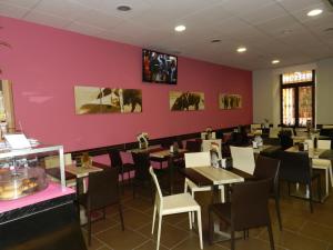 ein Restaurant mit Tischen und Stühlen und einer rosa Wand in der Unterkunft Plaza de Toros in Ronda