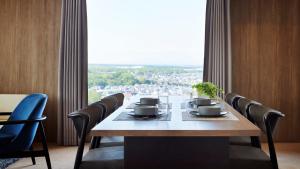 北广岛ES CON FIELD HOKKAIDO HOTEL Kitahiroshima Station的一张餐桌，几把椅子，还有一扇大窗户