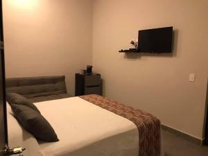 a bedroom with a bed and a flat screen tv at Hotel Playa Azul Sayulita in Sayulita