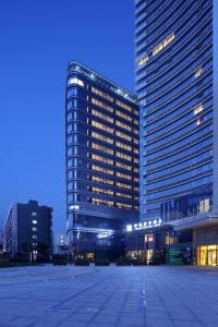 un grand bâtiment avec un parking en face de celui-ci dans l'établissement SSAW Boutique Hotel Hangzhou Wildwind, à Hangzhou