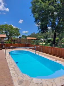 a large blue swimming pool with a wooden fence at Mini Casa Família in Brotas