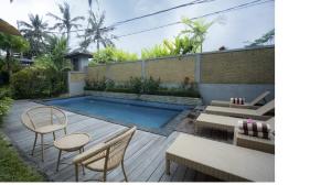 Un patio trasero con piscina y algunas sillas y mesas. en Villa Pondok Sadia, en Tegalalang