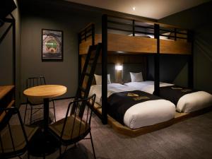 a bedroom with two bunk beds and a table and a stool at ES CON FIELD HOKKAIDO HOTEL Kitahiroshima Station in Kitahiroshima