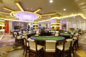 ein Casino mit Pokertischen und Stühlen sowie einem Kronleuchter in der Unterkunft Jeju Oriental Hotel & Casino in Jeju-do