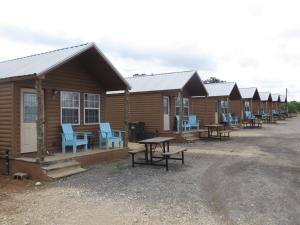 a row of wooden lodges with blue chairs and tables at All Tucked Inn Cabins in Stockdale