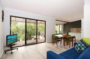 Una sala de estar con un sofá azul y una mesa. en All Decked Out at Hyams Beach by Experience Jervis, en Hyams Beach