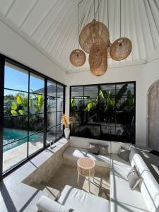 a living room with a white couch and some windows at White Shell Villas in Uluwatu