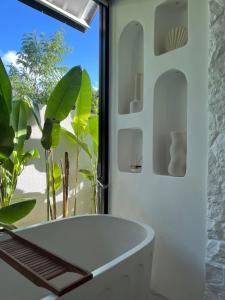a white bath tub in a bathroom with a window at White Shell Villas in Uluwatu +33 photos