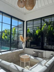 a living room with a couch and large windows at White Shell Villas in Uluwatu
