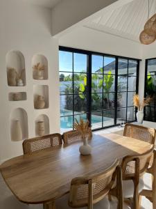 a dining room with a wooden table and chairs at White Shell Villas in Uluwatu
