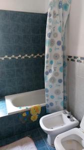 a bathroom with a tub and a toilet and a shower curtain at Casa a 800 mts de pleno centro - NO RECIBO GRUPO DE JOVENES in Villa Carlos Paz