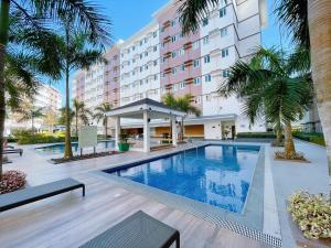 a swimming pool in front of a hotel with palm trees at Eco Suite Hope Residences Trece in Trece Martires