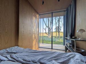 a bedroom with a bed and a large window at Tiny House Overlooking Nature in Vordingborg