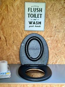 a toilet with a black seat and a sign on a wall at Small Cabin With Outdoor Kitchen By Forest Stream in Trollhättan